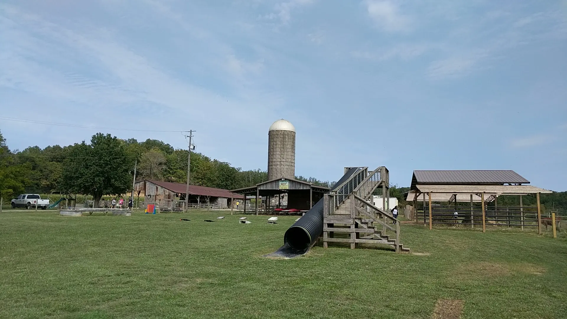 Outdoor activity where several children are tossing balls into a basket, practicing motor coordination.