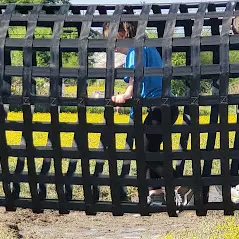 Children lining up to throw rings onto a bottle as part of a target game.